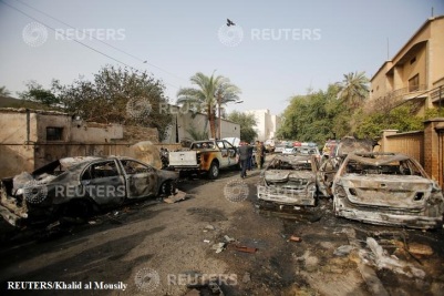 Members of Iraqi security forces gather at the site after a suicide car bomb attack in Baghdad