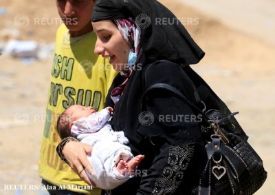 A displaced woman who fled from clashes carries her baby during a battle between Iraqi forces and Islamic state militants in western Mosul